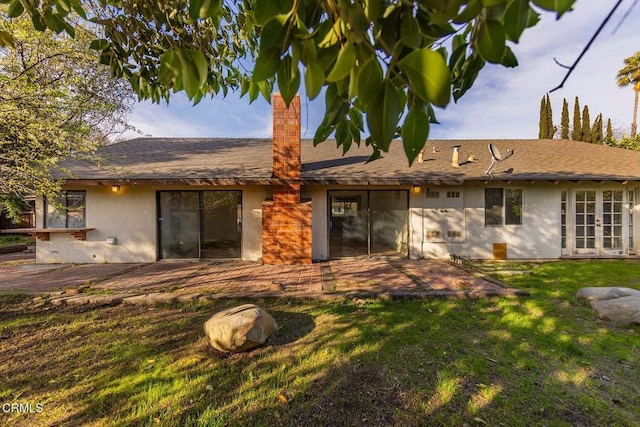 back of property with french doors, a patio area, a lawn, and stucco siding