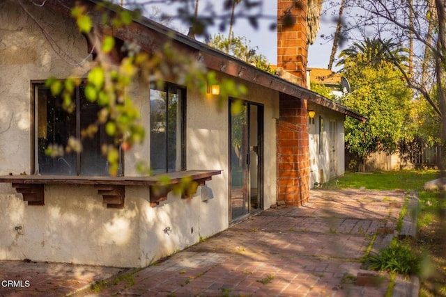 view of home's exterior featuring a patio, a chimney, and stucco siding