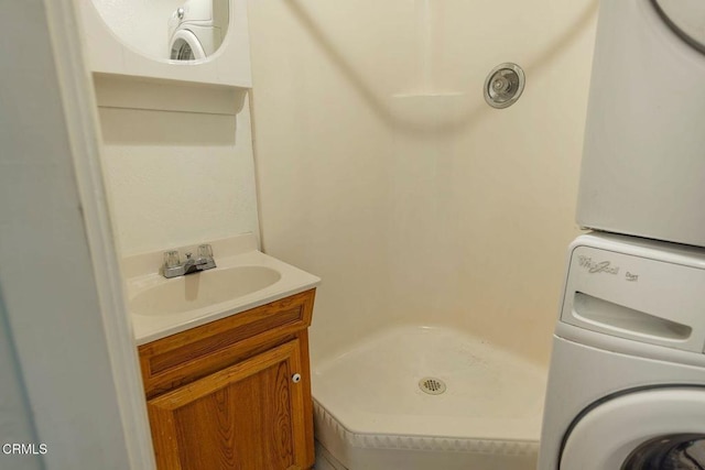 bathroom featuring stacked washer / drying machine, a shower stall, and vanity