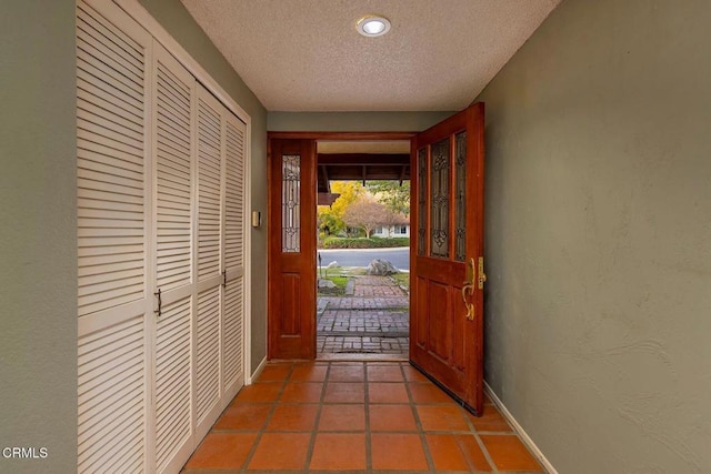 tiled entrance foyer featuring baseboards, a textured ceiling, and a textured wall