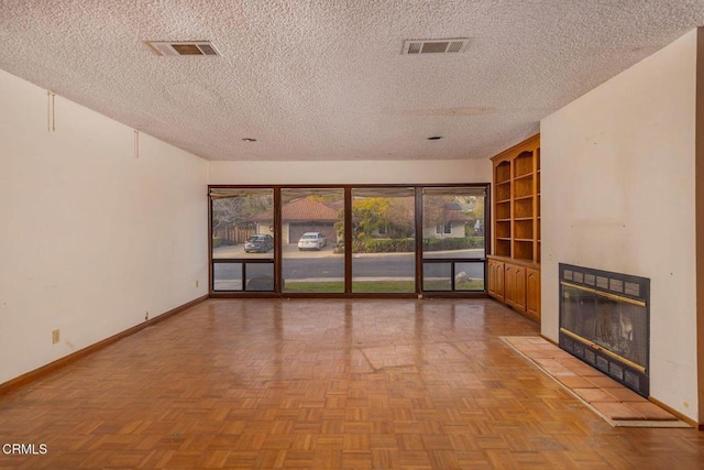 unfurnished living room with a textured ceiling, a tile fireplace, visible vents, and baseboards