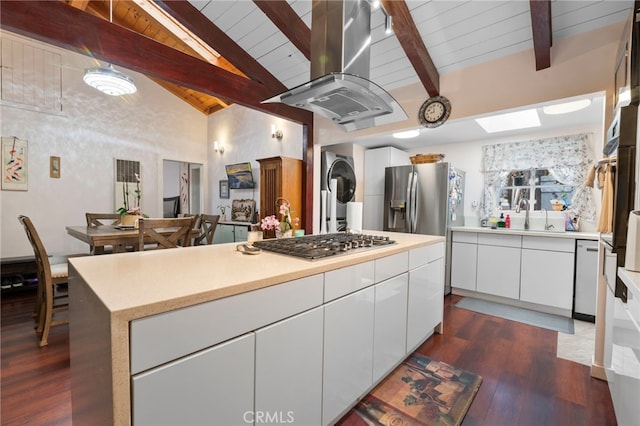 kitchen with stainless steel appliances, stacked washer / dryer, white cabinetry, light countertops, and island exhaust hood