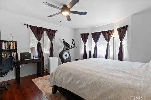 bedroom featuring ceiling fan, multiple windows, and wood finished floors