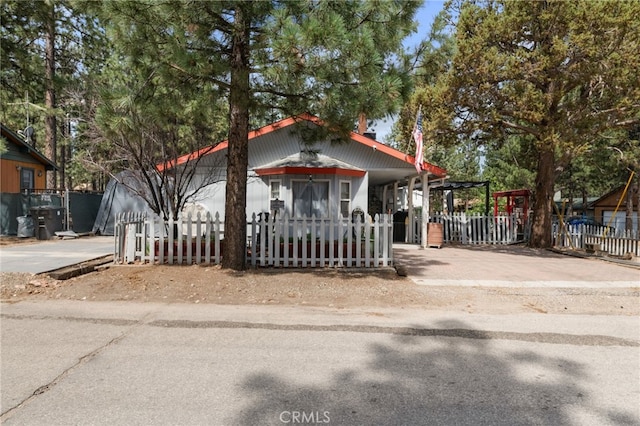 view of front of home with a fenced front yard, concrete driveway, and a carport