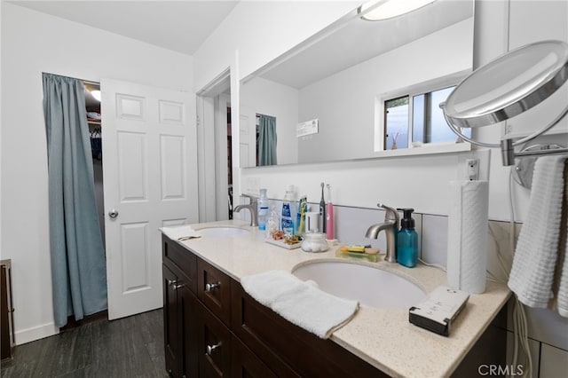 full bath with double vanity, wood finished floors, and a sink