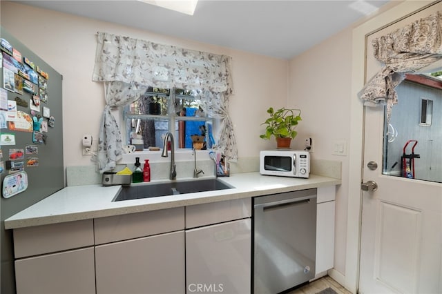 kitchen with appliances with stainless steel finishes, light countertops, and a sink