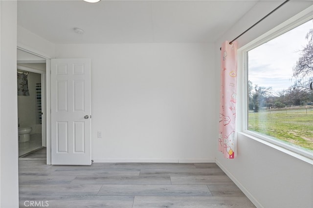 unfurnished room with light wood-type flooring and baseboards