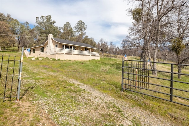 view of side of home with a gate, driveway, a chimney, and fence