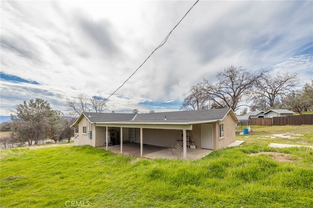 rear view of property featuring a patio area, fence, a lawn, and stucco siding