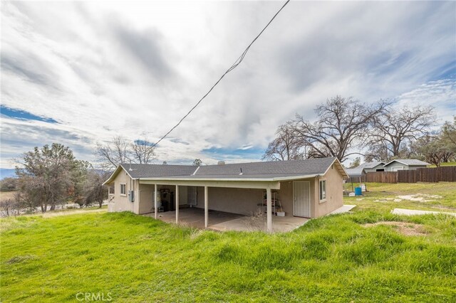 back of house with fence, a lawn, a patio area, and stucco siding