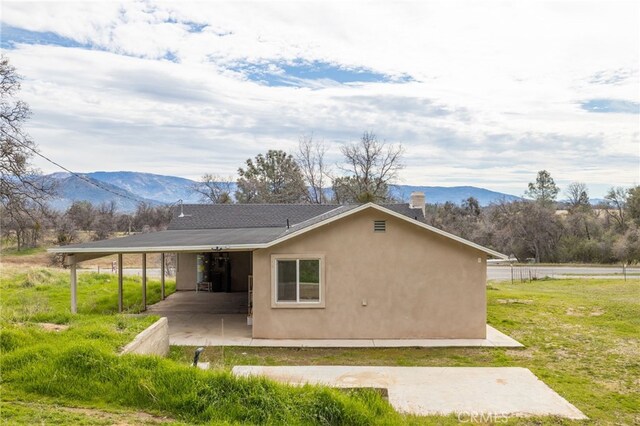 back of property with stucco siding, a mountain view, a patio area, and a yard