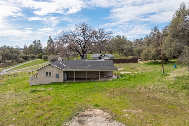 back of property with a lawn and fence