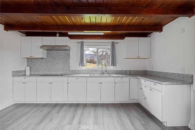 kitchen featuring beamed ceiling, black electric cooktop, wooden ceiling, and a sink