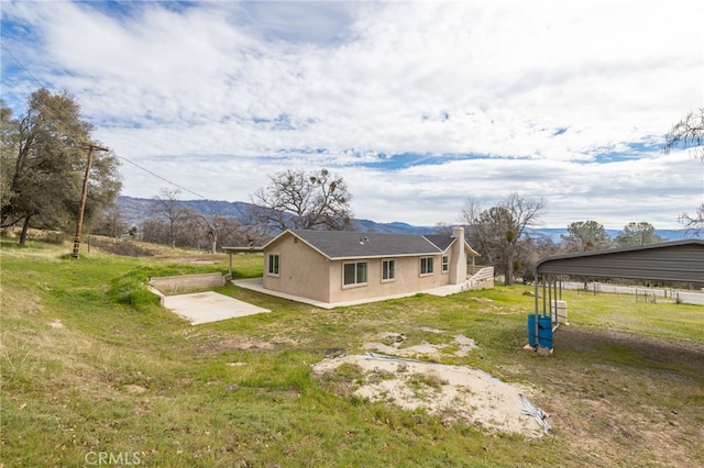 back of property featuring a yard, a patio, a mountain view, and stucco siding