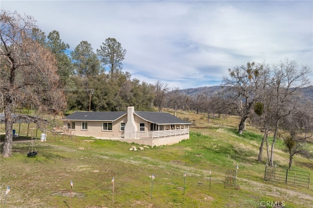 rear view of property featuring a rural view, fence, and a chimney