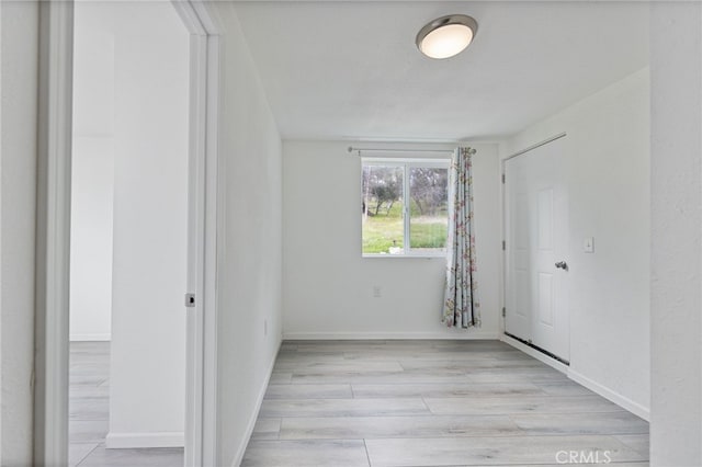 unfurnished room with light wood-style flooring and baseboards