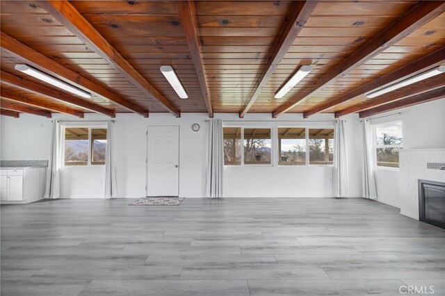 unfurnished living room featuring a glass covered fireplace, wooden ceiling, wood finished floors, and beam ceiling