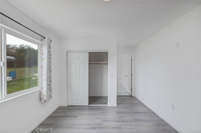 unfurnished bedroom featuring a closet, baseboards, and wood finished floors