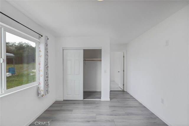 unfurnished bedroom with wood finished floors, a closet, and baseboards
