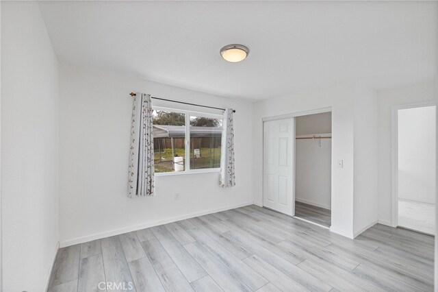 unfurnished bedroom featuring wood finished floors, a closet, and baseboards