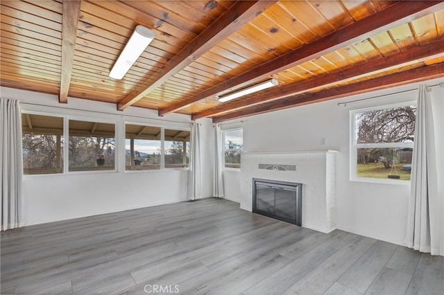 unfurnished living room featuring a brick fireplace, beam ceiling, wooden ceiling, and wood finished floors