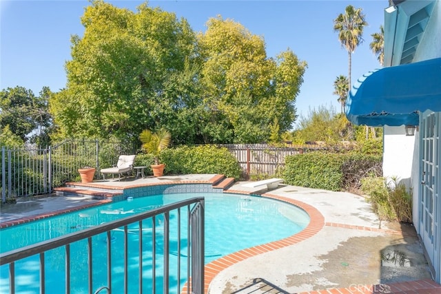 view of pool with a fenced in pool, a patio area, fence, and a diving board