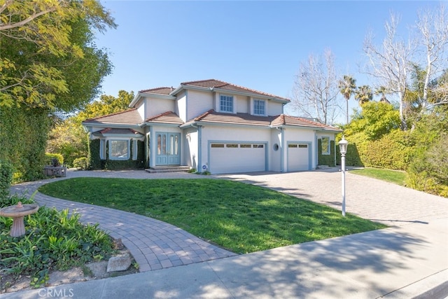 mediterranean / spanish-style home with a garage, a front yard, decorative driveway, and a tiled roof