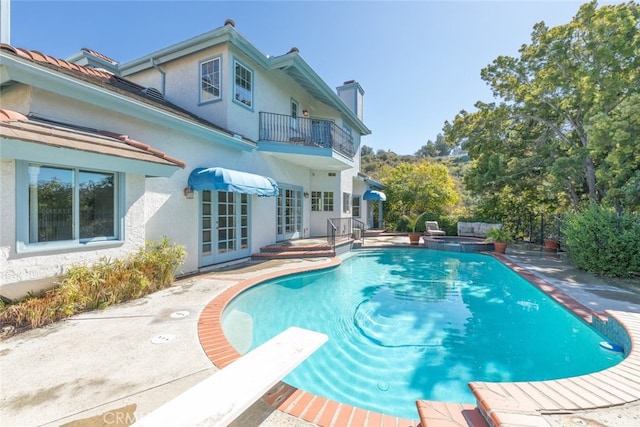 view of pool with a diving board, a patio, french doors, and a pool with connected hot tub