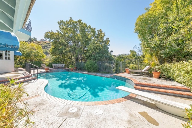 view of pool featuring a pool with connected hot tub, a patio area, fence, and a diving board