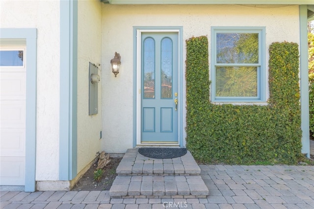 entrance to property featuring a garage and stucco siding