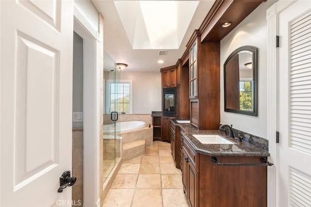 bathroom featuring a garden tub, stone tile floors, visible vents, vanity, and a stall shower