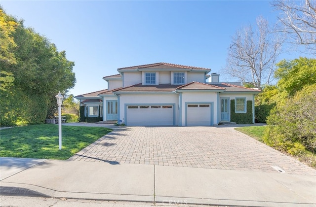 view of front of house with a garage, a front yard, decorative driveway, and a chimney