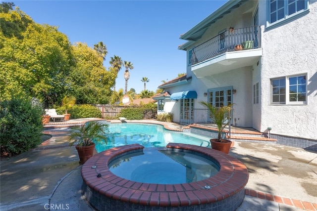 view of swimming pool with a pool with connected hot tub, a patio, french doors, and fence