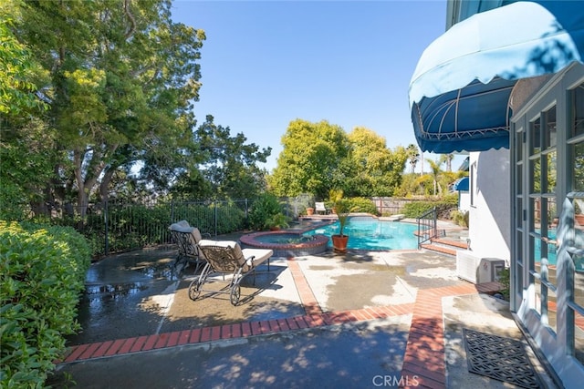 view of swimming pool with a patio, a fenced backyard, and a pool with connected hot tub