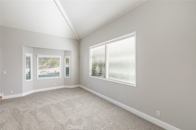 empty room with lofted ceiling, light carpet, and baseboards