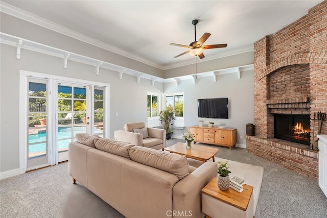 living room with light colored carpet, a ceiling fan, ornamental molding, a brick fireplace, and baseboards