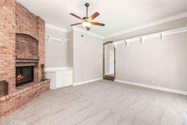 unfurnished living room with carpet floors, ornamental molding, a brick fireplace, and baseboards