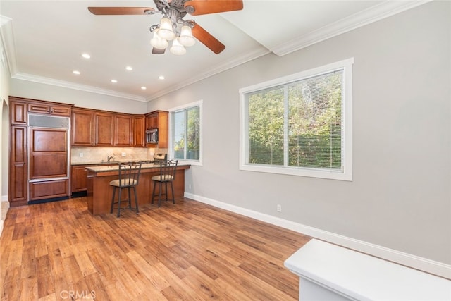 kitchen featuring a peninsula, baseboards, light wood-type flooring, backsplash, and stainless steel microwave