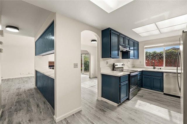 kitchen with plenty of natural light, arched walkways, a sink, under cabinet range hood, and appliances with stainless steel finishes