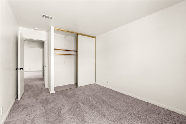 unfurnished bedroom with light carpet, visible vents, baseboards, and a closet