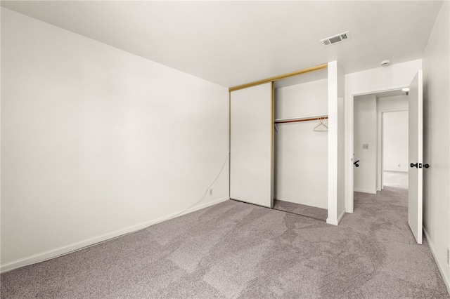 unfurnished bedroom with baseboards, visible vents, a closet, and light carpet