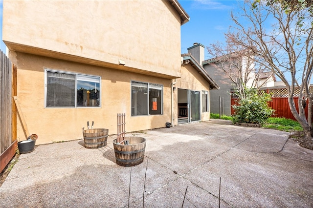 rear view of house with a patio, fence, a chimney, and stucco siding