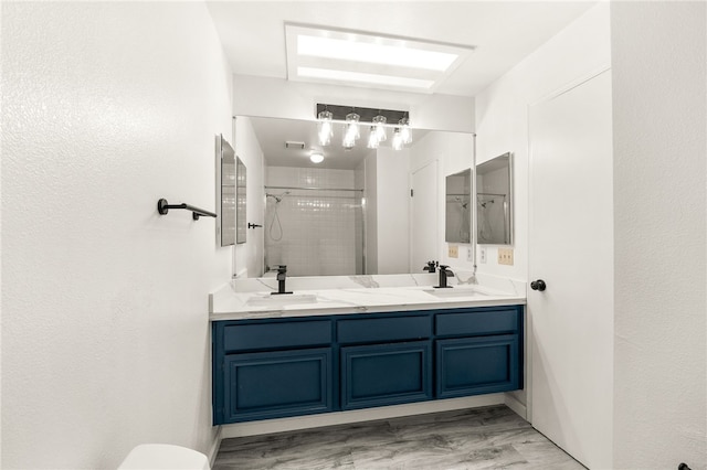 bathroom with a sink, visible vents, tiled shower, and double vanity