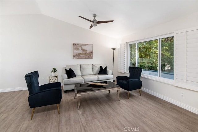 living area featuring lofted ceiling, baseboards, and wood finished floors