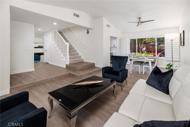 living area with visible vents, vaulted ceiling, stairway, and wood finished floors