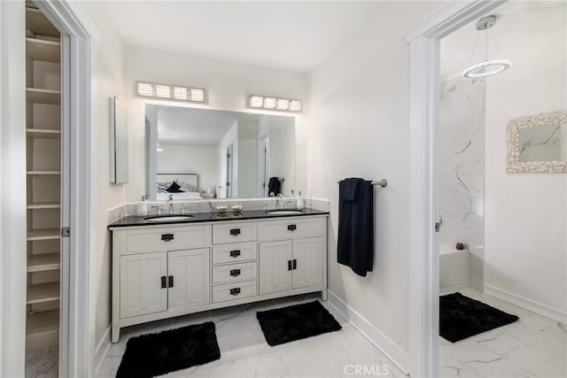 full bathroom featuring double vanity, marble finish floor, baseboards, and a sink