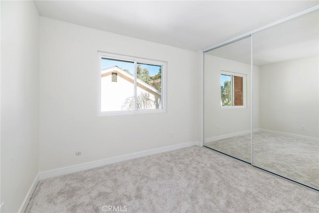 unfurnished bedroom featuring a closet, baseboards, and carpet flooring