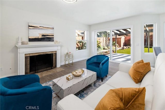 living room featuring baseboards, a tiled fireplace, and wood finished floors