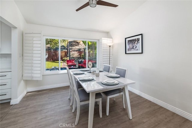 dining area featuring a ceiling fan, lofted ceiling, baseboards, and wood finished floors