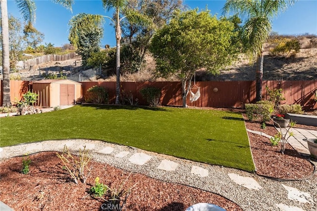 view of yard featuring an outbuilding, a fenced backyard, and a storage shed